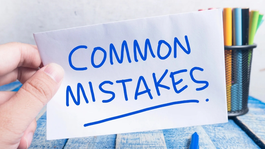 Hand holding a paper with the words "Common Mistakes" written in blue marker.