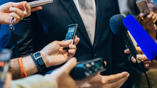 Businessman speaking into a microphone while addressing a group of reporters at a press event